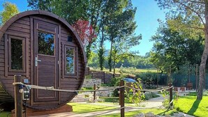Una cabaña de madera con diseño circular, una barrera de cuerda y un camino de piedra que la conduce.