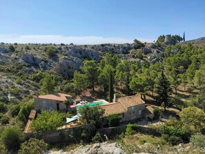 Ein Steinhaus mit Swimmingpool, umgeben von Bäumen und felsigem Gelände.