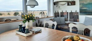 A cozy seating area with a view of the landscape, a table with candles, and a bowl of fruit. - Holiday home with view over Limfjord (Thyholm)