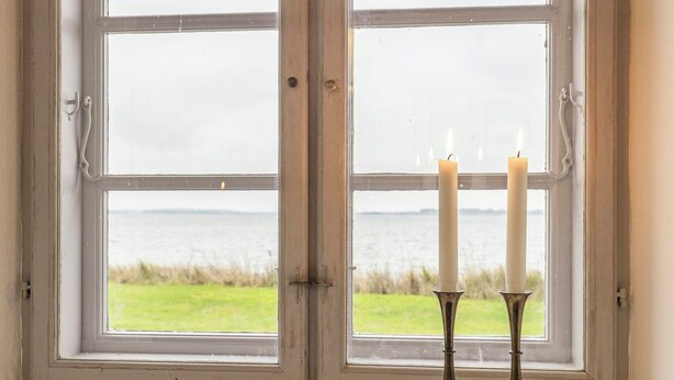 A window with a view of a grassy field and water.