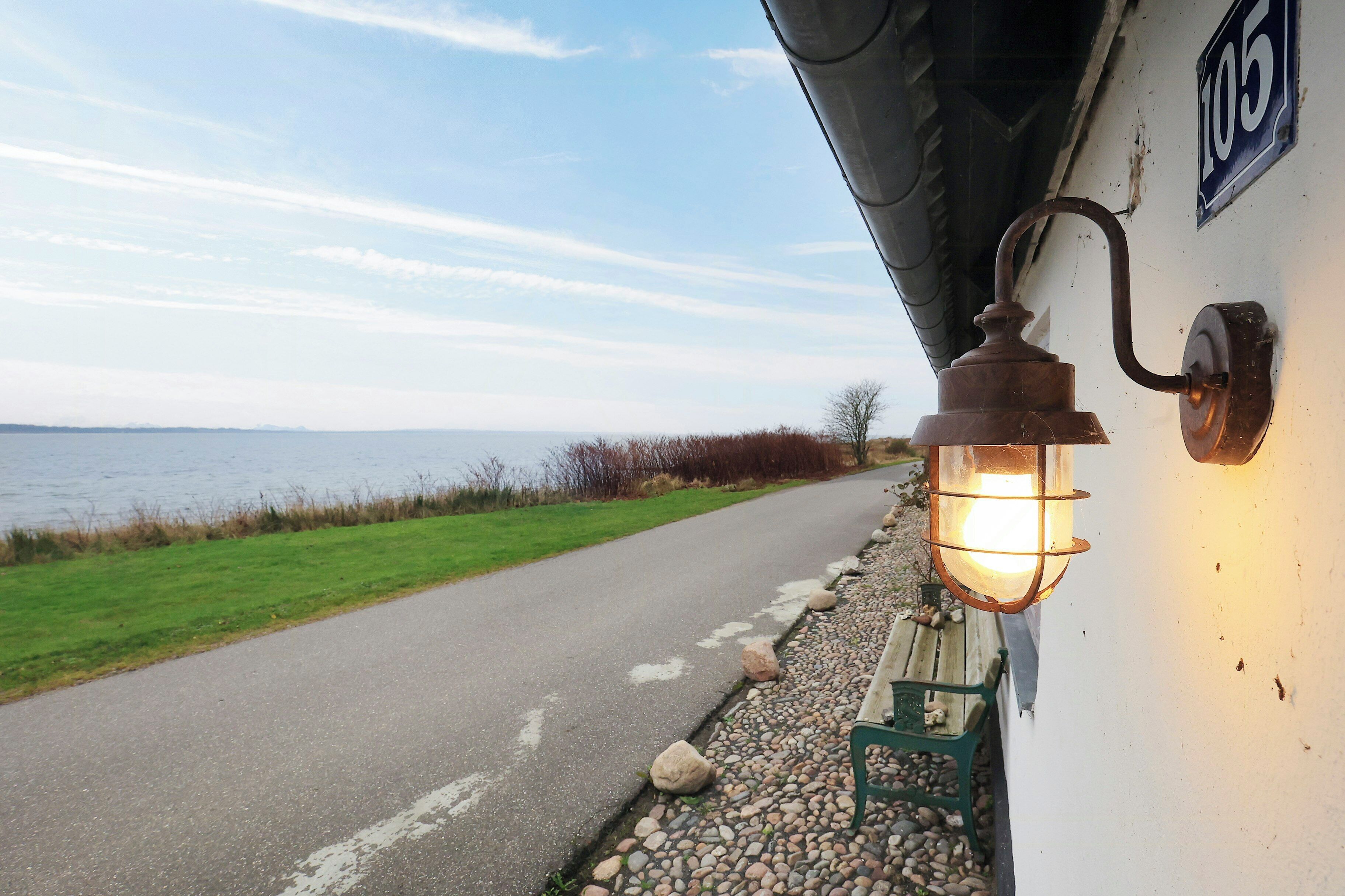 A pathway leading to a building with a number sign, a bench, and a lamp post.