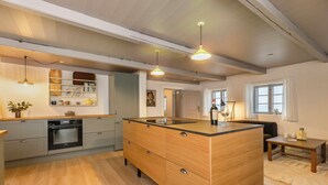 A modern kitchen with a central island, built-in oven, and wooden cabinetry.