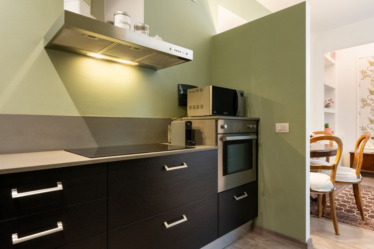 A compact kitchen with a microwave, oven, and a built-in range hood.