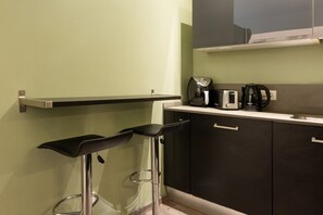 A kitchen with two bar stools, a coffee maker, a toaster, and a kettle on the counter. - La Casa di Flora - 6-bedroom suite apartment with private parking (Florence)
