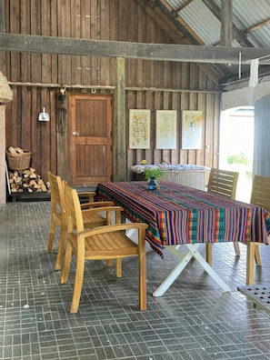 A rustic wooden dining area with a table set for four, chairs, a wooden bench, and a door with artwork on the walls.