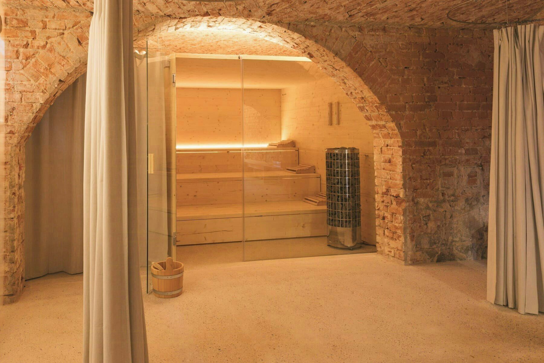 A spa room with a wooden bench, a sauna, and a stone wall.