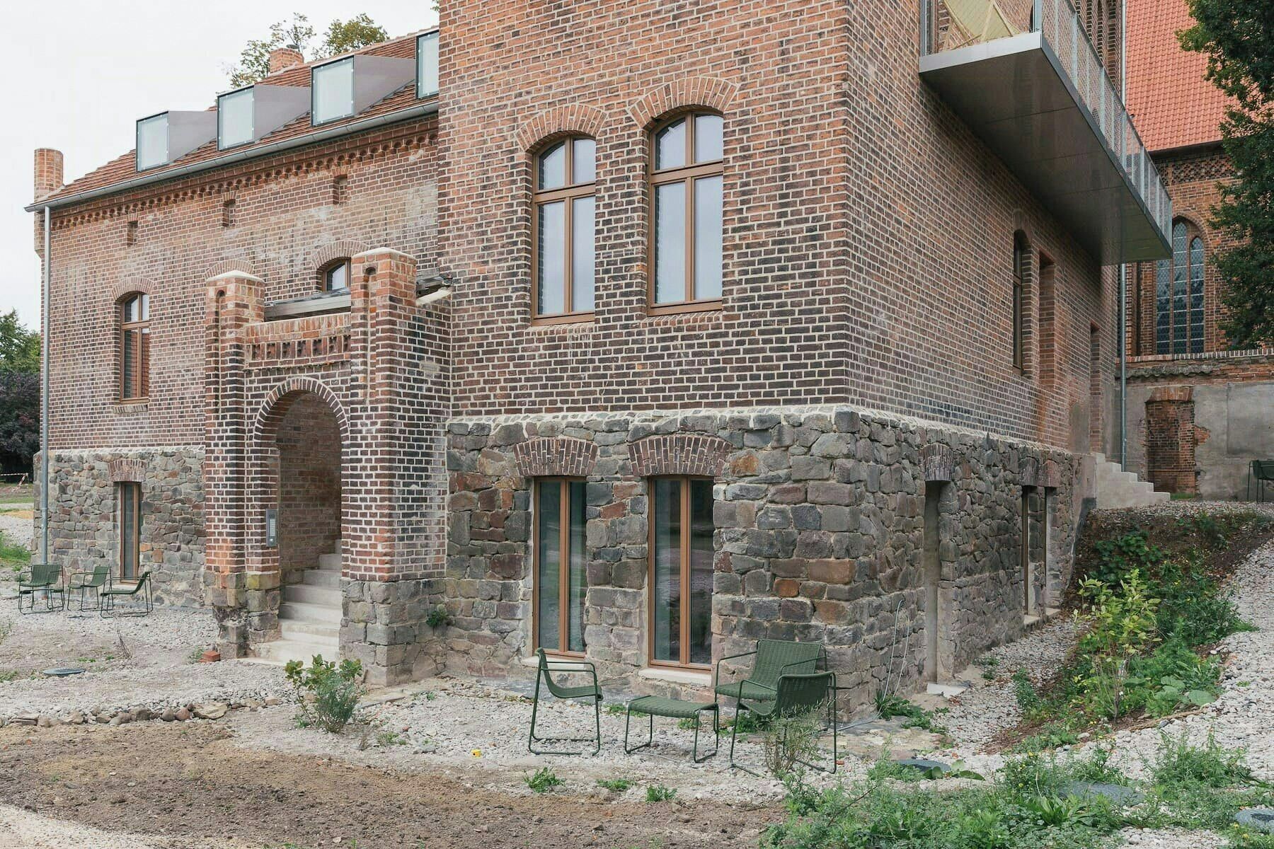 A brick building with stone accents, multiple windows, and outdoor seating.