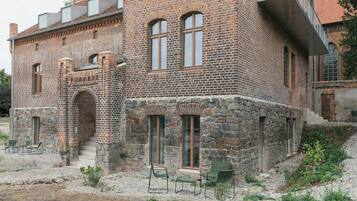 A brick building with stone accents, multiple windows, and outdoor seating.