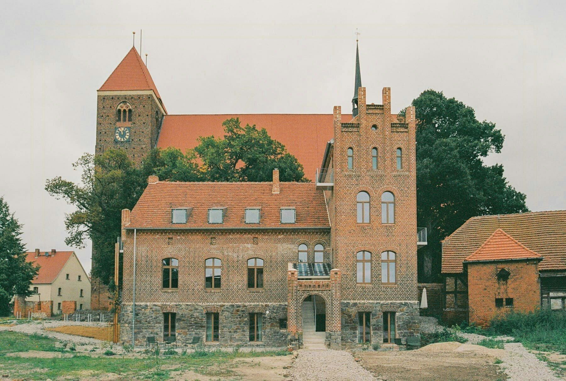 Ein historisches Gebäude mit einem markanten Turm, zahlreichen Fenstern und einer Steinbasis.