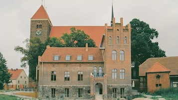 Ein historisches Gebäude mit einem markanten Turm, zahlreichen Fenstern und einer Steinbasis.