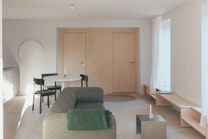 Ein minimalistisches Wohnzimmer mit einer Couch, einem runden Tisch und einer Tür.