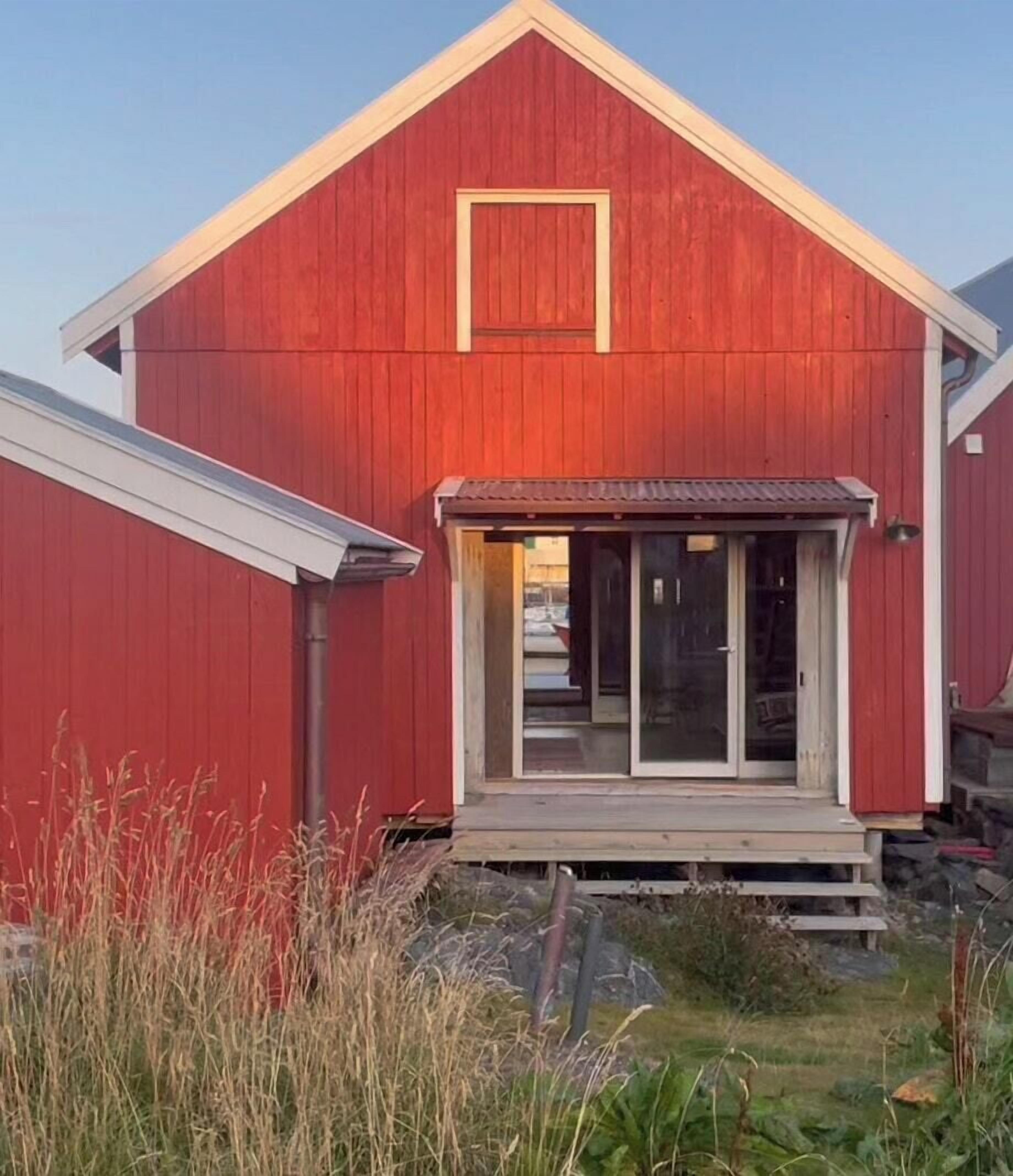 A red barn with a front door, a small porch, and a clear sky.
