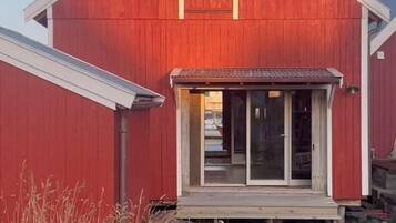 A red barn with a front door, a small porch, and a clear sky.
