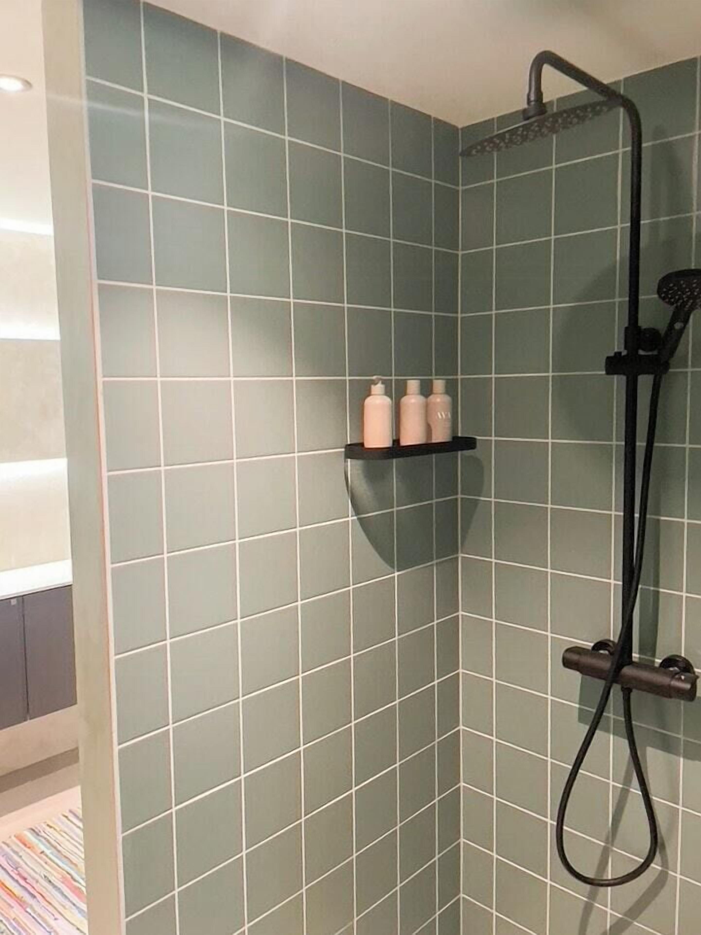 Un espace douche équipé d’un pommeau de douche à main et d’un robinet mural.