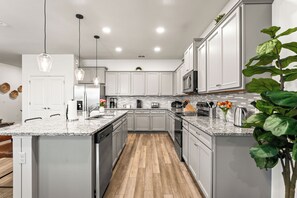 Eine moderne Küche mit Granit Arbeitsplatten, Edelstahlgeräten und einer zentralen Kochinsel.
