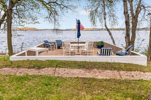 A deck with outdoor seating, a flag, and a view of a lake.