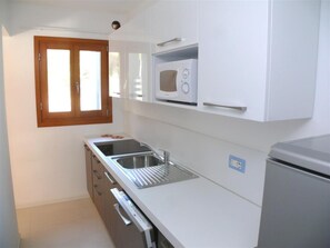 Eine kleine Küche mit Mikrowelle, Spüle und Kühlschrank.