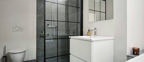 Un bagno moderno con box doccia in vetro, un lavandino bianco e uno specchio grande.