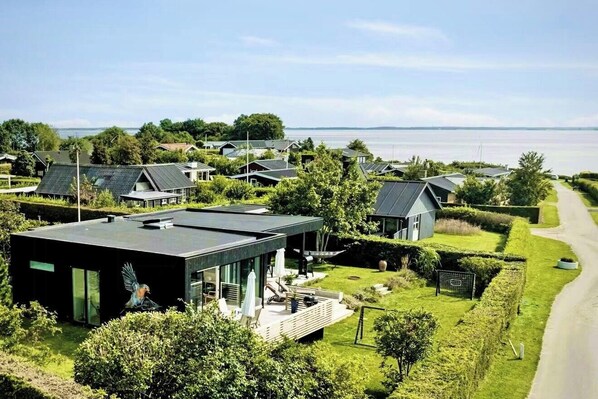 Ein modernes Wohngebiet mit Häusern, die mit Solaranlagen ausgestattet sind, mit Blick auf das Meer und gepflegten Gärten.