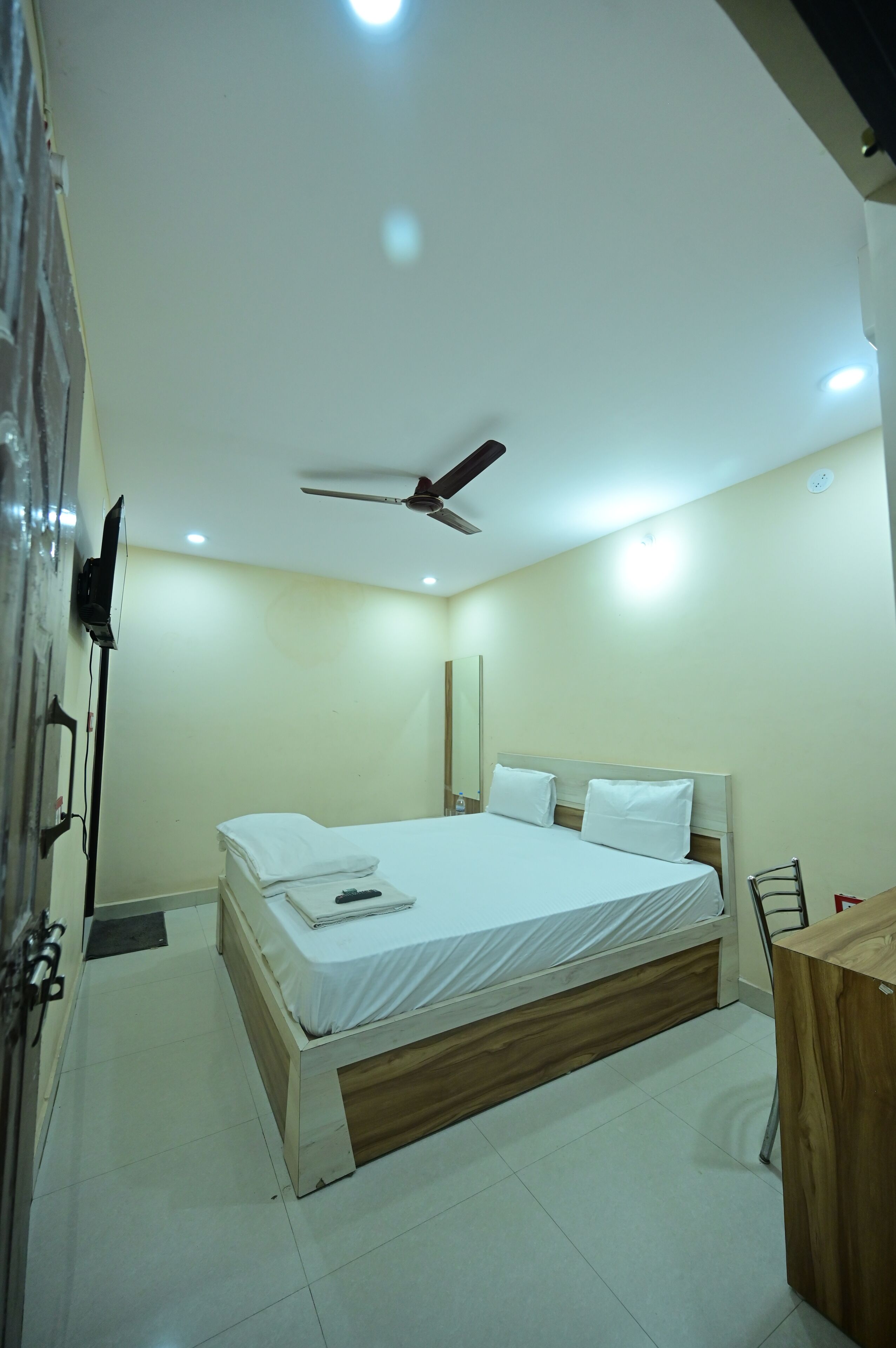 A bedroom with a bed, ceiling fan, and a desk.