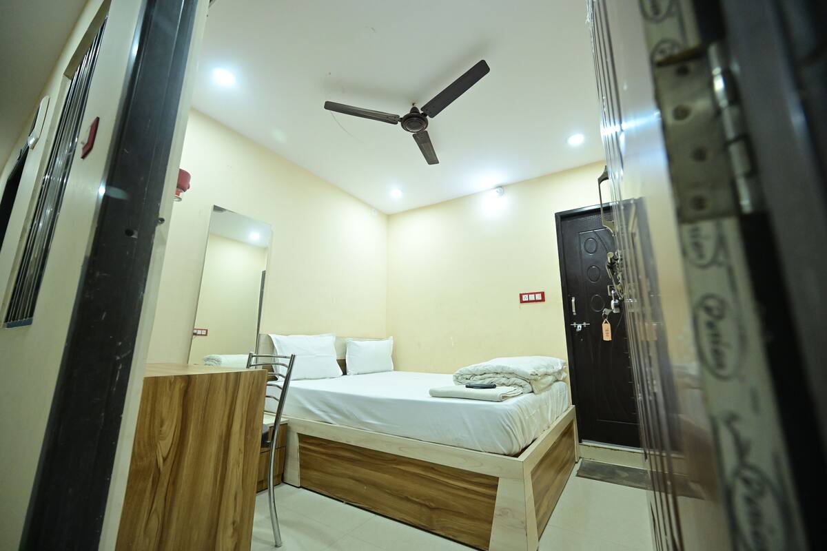 A bedroom with a bed, a ceiling fan, a wooden dresser, and a door with a lock.