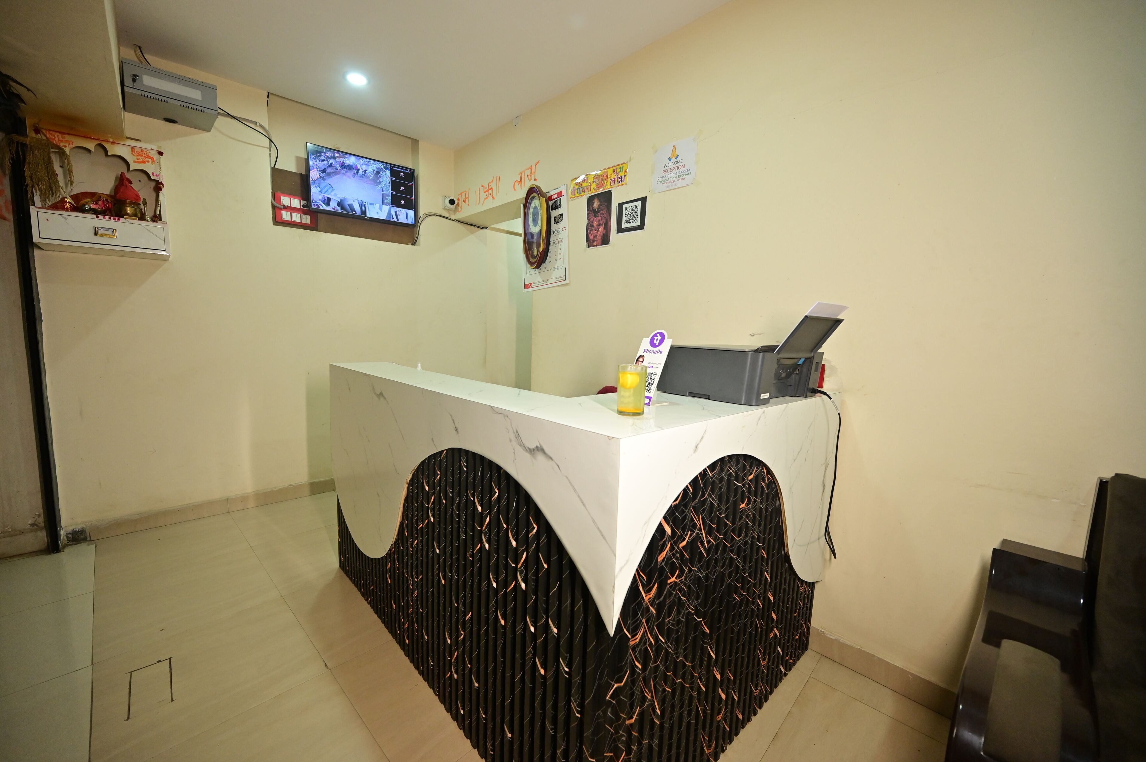 A reception desk with a TV, a calendar, and a QR code on the wall.
