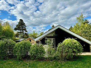 Ein modernes Haus mit geneigtem Dach, umgeben von üppiger Vegetation und Bäumen.