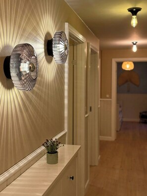 A hallway with a light fixture, a potted plant, and a door. - Modern family house near beach in Odsherred (Vig)