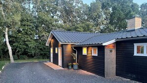 Ein kleines, dunkles Holzhaus mit einem Schotterweg und einem Metalldach.