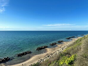 Eine Küstenlandschaft mit klarem, blauem Wasser, einem Sandstrand und Felsformationen.