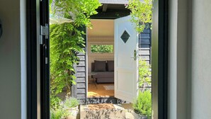 A doorway leading to a room with a sofa, a small table, and potted plants. - Renovated wooden house at Vejby Beach (Vejby)