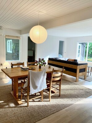Ein modernes Interieur mit einem Holztisch, Stühlen, einer Bank und einer Hängelampe.