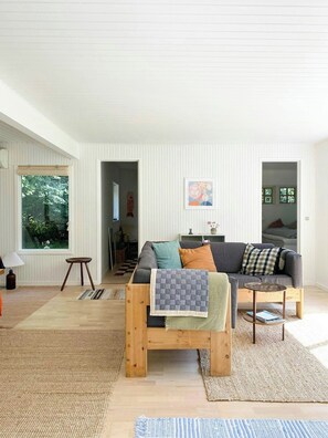 Ein modernes Wohnzimmer mit einer Couch, einem Couchtisch und Blick auf einen Garten durch ein Fenster.