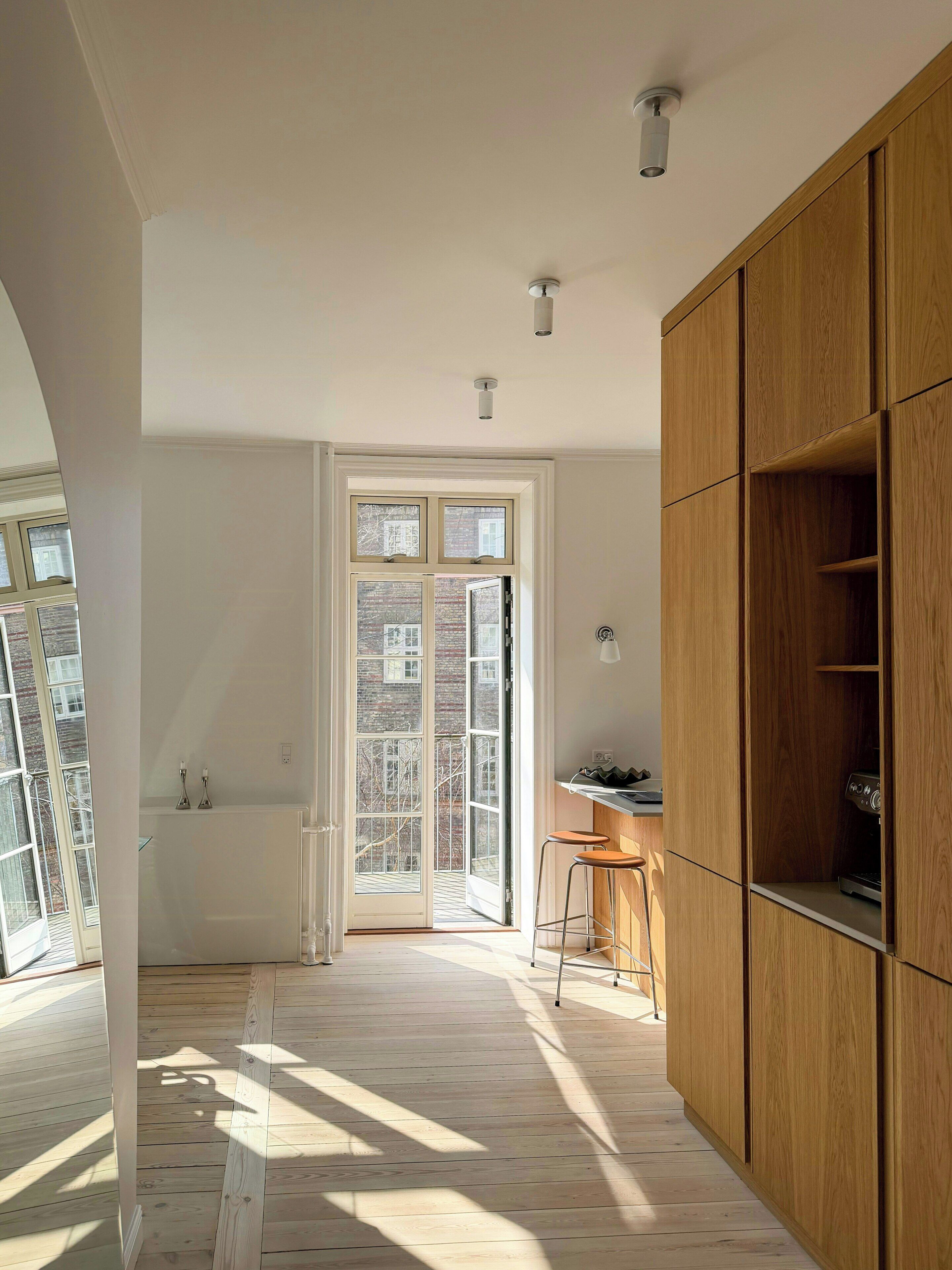 A modern kitchen with wooden cabinets, a built-in oven, and a large window.