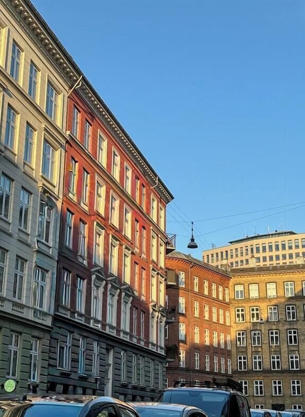 A multi-story building with a classic architectural style, featuring a mix of window designs and a prominent red facade. - Design flat between Frederiksberg and Vesterbro (København)