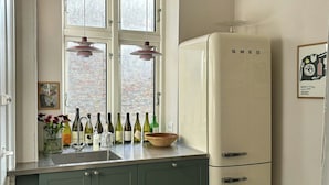 A kitchen with a window, a refrigerator, and a gas stove. - Design flat between Frederiksberg and Vesterbro (København)