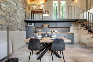 Una cucina moderna con una parete in pietra, un tavolo da pranzo con sedie e una scala.