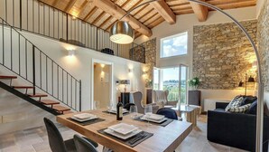 A spacious living area with a wooden dining table, black chairs, a staircase, and a stone wall. - Villa with infinity pool in the Tuscan hills (Rignano sull'arno)