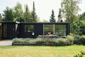 Ein modernes schwarzes Haus mit Glastür, die zu einer Terrasse führt.