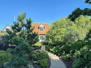 A residential property with a pathway leading to a house with a tiled roof and a small window. - Half-timbered house with harbor view in Ebeltoft (Ebeltoft)