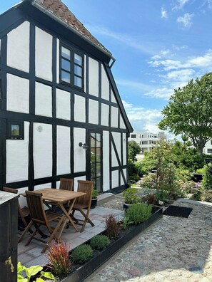 Un bâtiment à colombages doté d’un patio comprenant une table et des chaises.