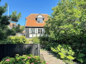 A traditional house with a tiled roof, surrounded by lush greenery and a wooden fence. - Half-timbered house with harbor view in Ebeltoft (Ebeltoft)