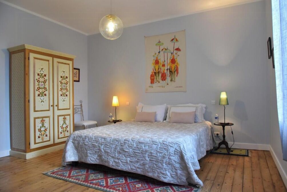 A bedroom with a bed, two bedside tables, a wardrobe, and a wall-mounted lamp.