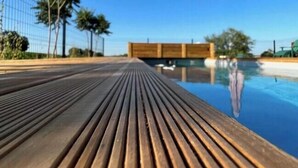 A wooden deck leading to a pool with a clear blue sky above.