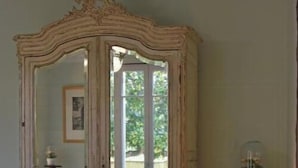 A room with a large mirror, a bed, a lamp, and a window.