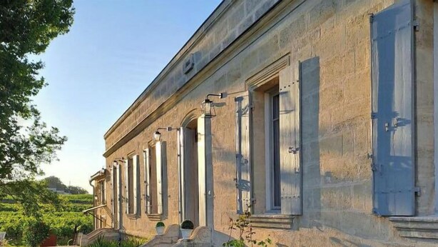 A building with a long facade, large windows, and a stone pathway leading to the entrance.