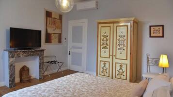 A bedroom with a bed, a television on a stand, a wardrobe, and a lamp.