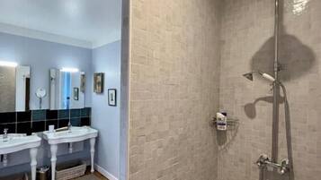 A bathroom with two sinks, a shower, and a tiled wall.