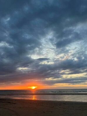 Ein Strand mit Sonnenuntergang und bewölktem Himmel.