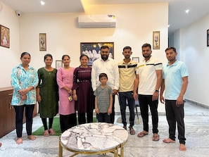 A group of people standing in a room with a marble floor, a round table, and framed artwork on the walls. - Hotel AeroFly By SS Group (New Delhi)